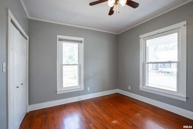 unfurnished bedroom with a closet, dark wood-style floors, baseboards, ceiling fan, and ornamental molding
