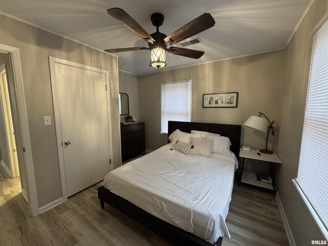 bedroom featuring ornamental molding, wood finished floors, and multiple windows