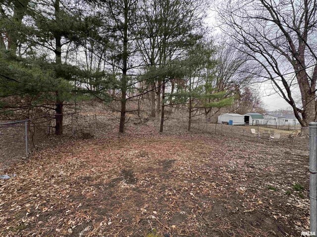 view of yard featuring fence, an outbuilding, and a storage unit