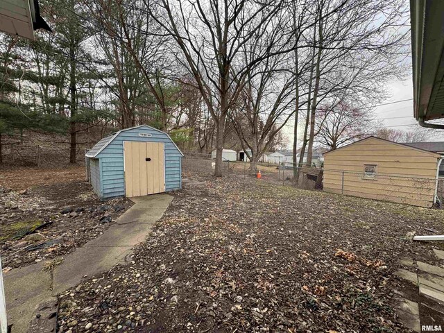view of yard featuring a storage shed, fence, and an outbuilding