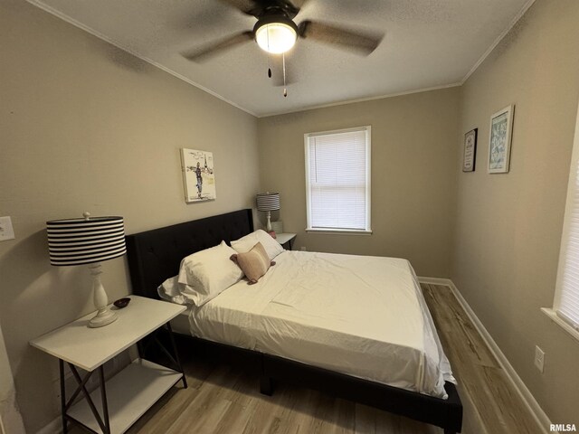 bedroom with crown molding, wood finished floors, baseboards, ceiling fan, and a textured ceiling