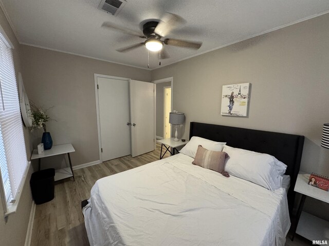 bedroom featuring visible vents, multiple windows, ornamental molding, and light wood-style floors