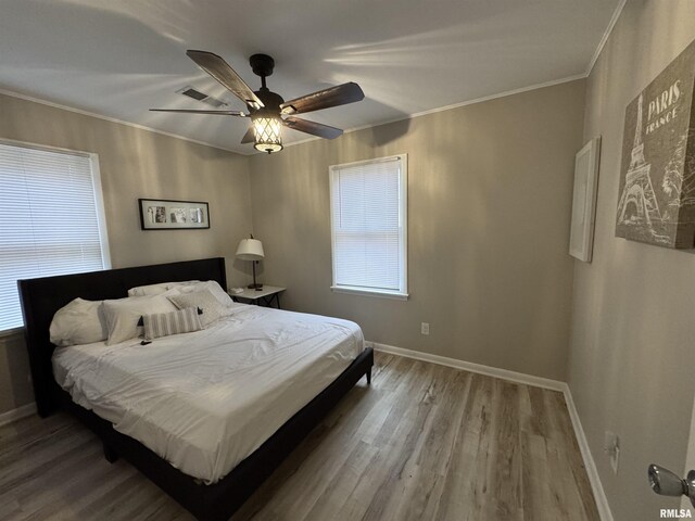 bedroom with baseboards, ceiling fan, ornamental molding, and wood finished floors