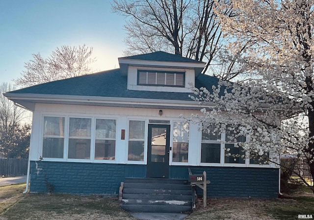 bungalow with a sunroom and roof with shingles