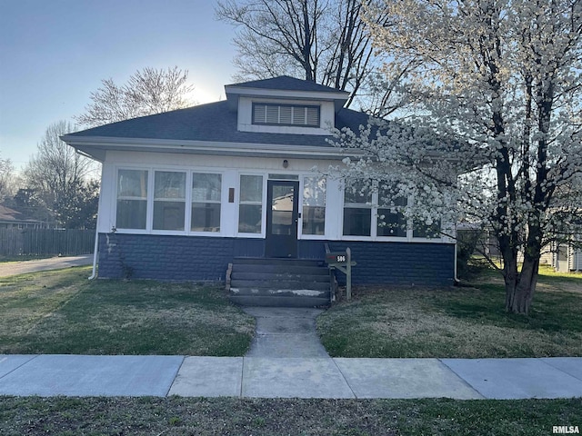 bungalow-style house featuring fence, roof with shingles, and a front yard