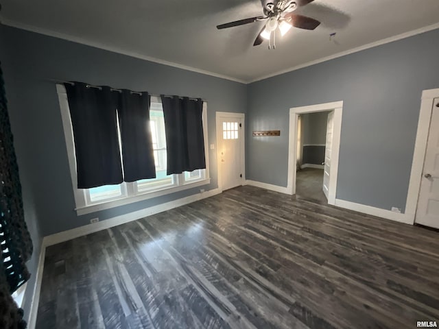 empty room featuring dark wood-type flooring, a ceiling fan, baseboards, and crown molding