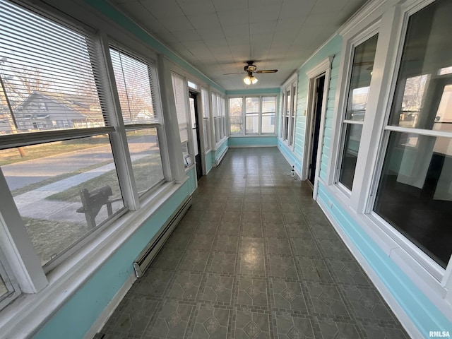 unfurnished sunroom featuring tile patterned floors and a baseboard heating unit