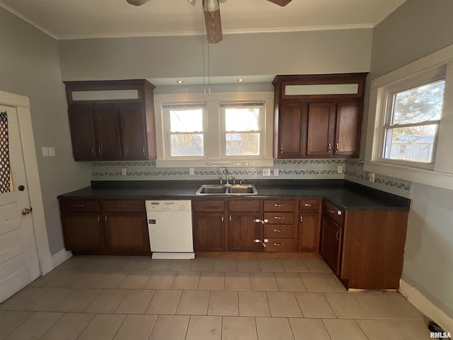 kitchen with dark countertops, white dishwasher, a sink, and tasteful backsplash