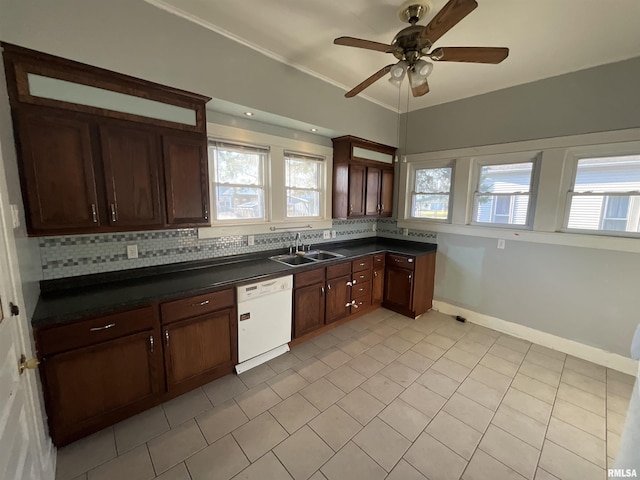 kitchen with backsplash, dark countertops, a sink, and white dishwasher