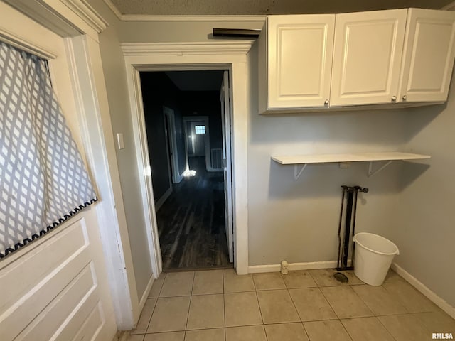 laundry area featuring baseboards, cabinet space, and light tile patterned floors