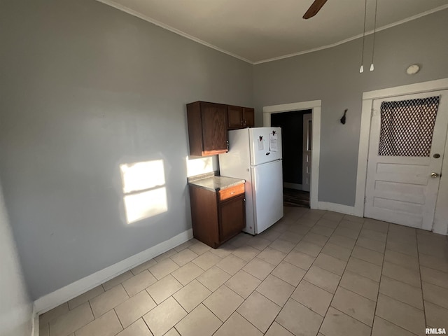 kitchen featuring light countertops, light tile patterned floors, ornamental molding, baseboards, and freestanding refrigerator