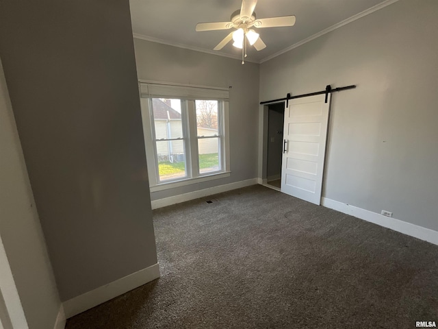 unfurnished bedroom featuring dark carpet, crown molding, a barn door, and baseboards