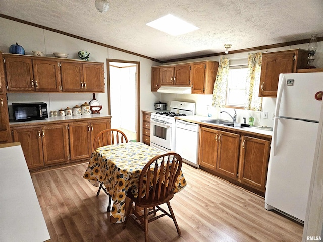 kitchen with white appliances, a sink, lofted ceiling, ornamental molding, and a textured ceiling