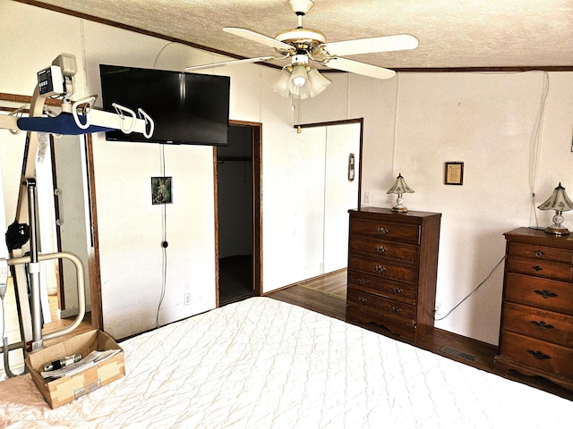 bedroom with wood finished floors, a closet, a textured ceiling, ornamental molding, and a ceiling fan