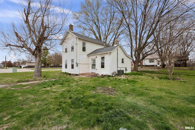 exterior space featuring roof with shingles, central AC, a chimney, and a lawn
