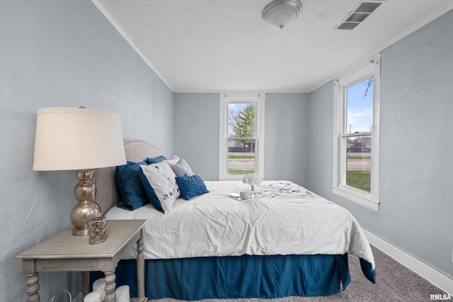 bedroom with crown molding, visible vents, carpet floors, a textured wall, and baseboards