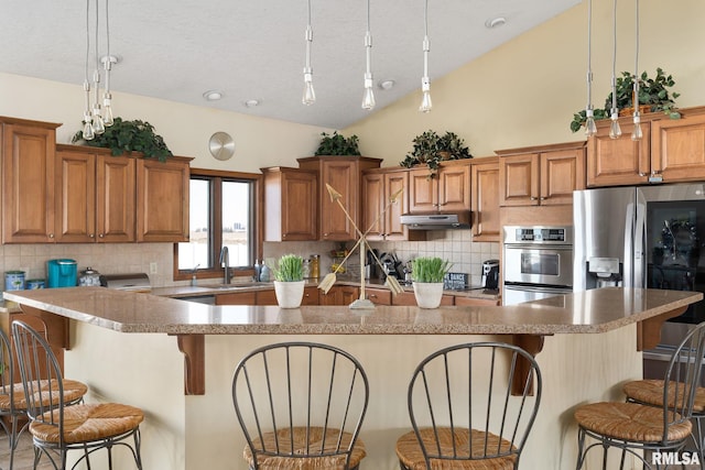 922 W Scott St, Eldridge, IA 52748 - kitchen featuring backsplash, a sink, a kitchen bar, brown cabinets, and under cabinet range hood