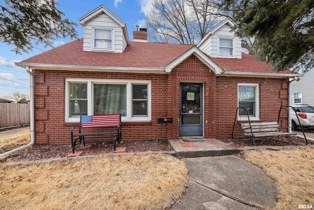 view of front of property featuring roof with shingles, entry steps, fence, brick siding, and a chimney