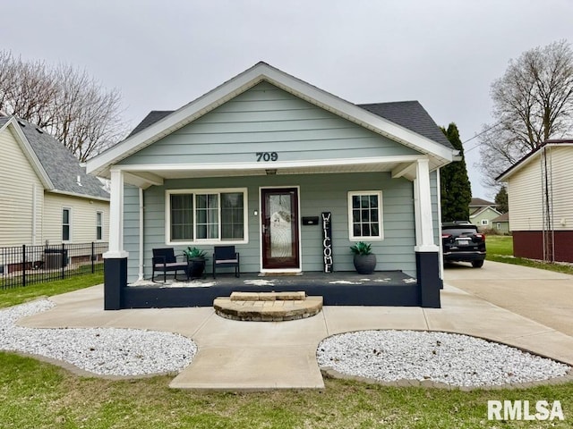 bungalow-style house featuring covered porch and fence