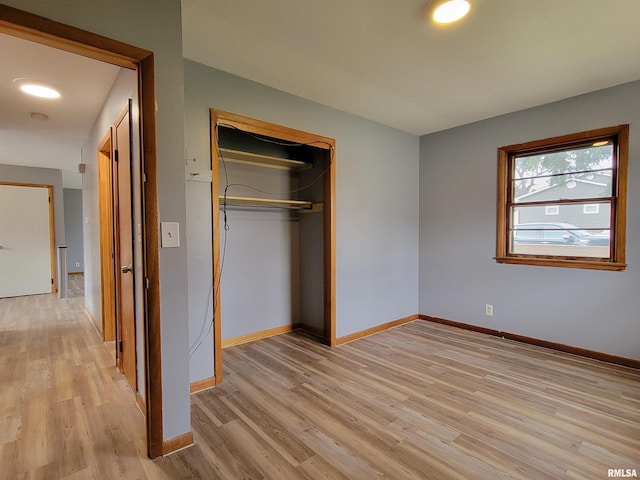 unfurnished bedroom featuring baseboards, a closet, and light wood-style flooring