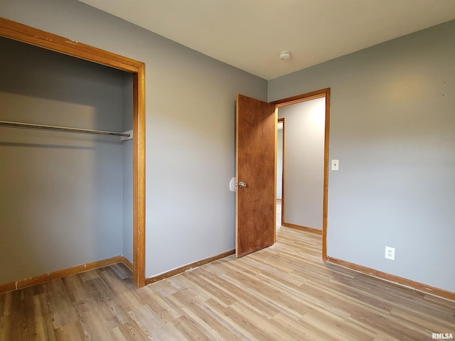 unfurnished bedroom with a closet, baseboards, and light wood-type flooring