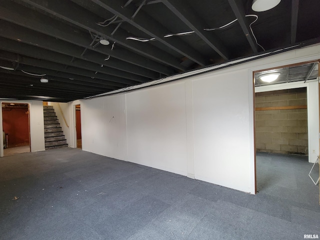 finished basement featuring concrete block wall and stairway