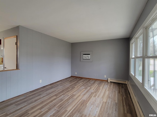 empty room featuring a baseboard radiator, a wall unit AC, and light wood finished floors