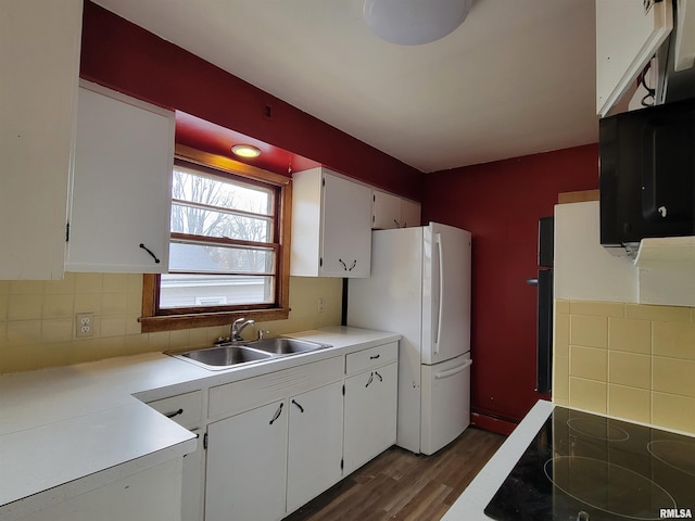 kitchen featuring black electric cooktop, white cabinets, a sink, and freestanding refrigerator