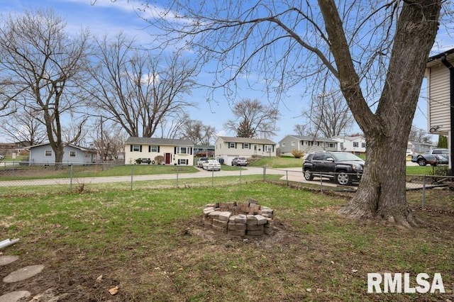 view of yard featuring an outdoor fire pit, a residential view, and fence