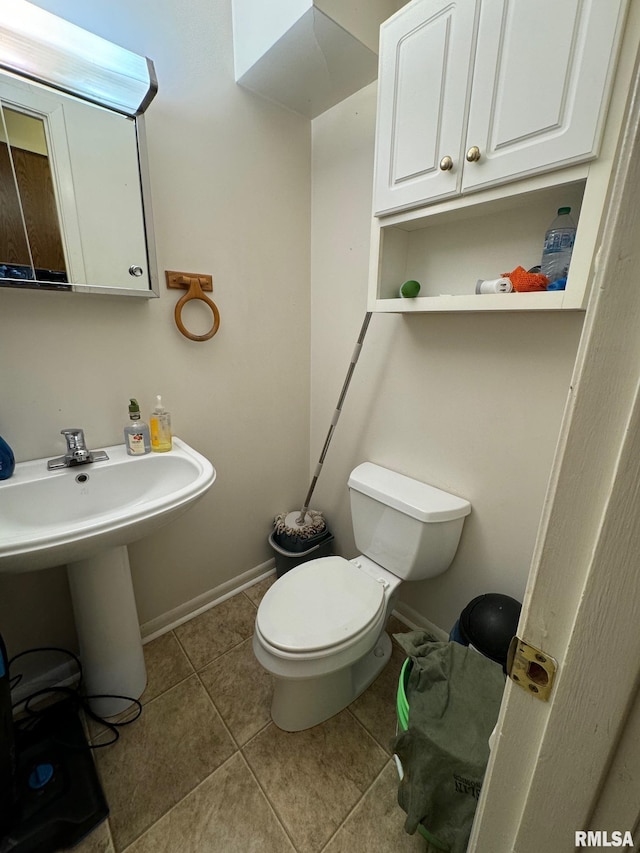 bathroom with toilet, a sink, baseboards, and tile patterned flooring