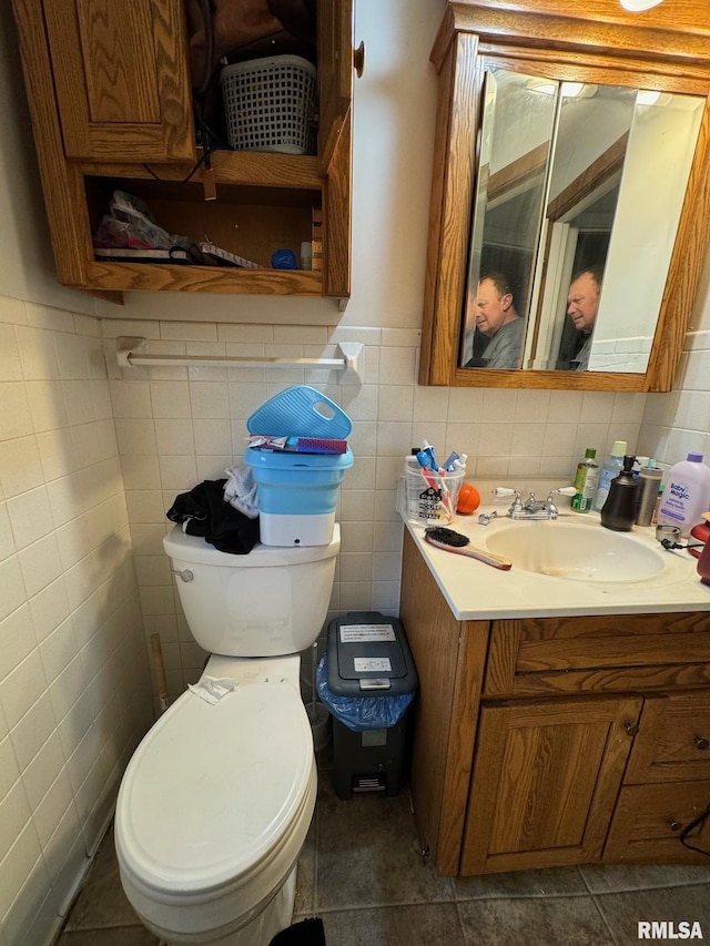 bathroom with vanity, tile patterned floors, a wainscoted wall, toilet, and tile walls