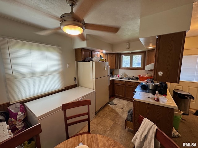 kitchen featuring light countertops, a peninsula, freestanding refrigerator, and ceiling fan