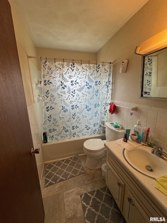 bathroom featuring vanity, toilet, wainscoting, shower / bath combo with shower curtain, and tile walls