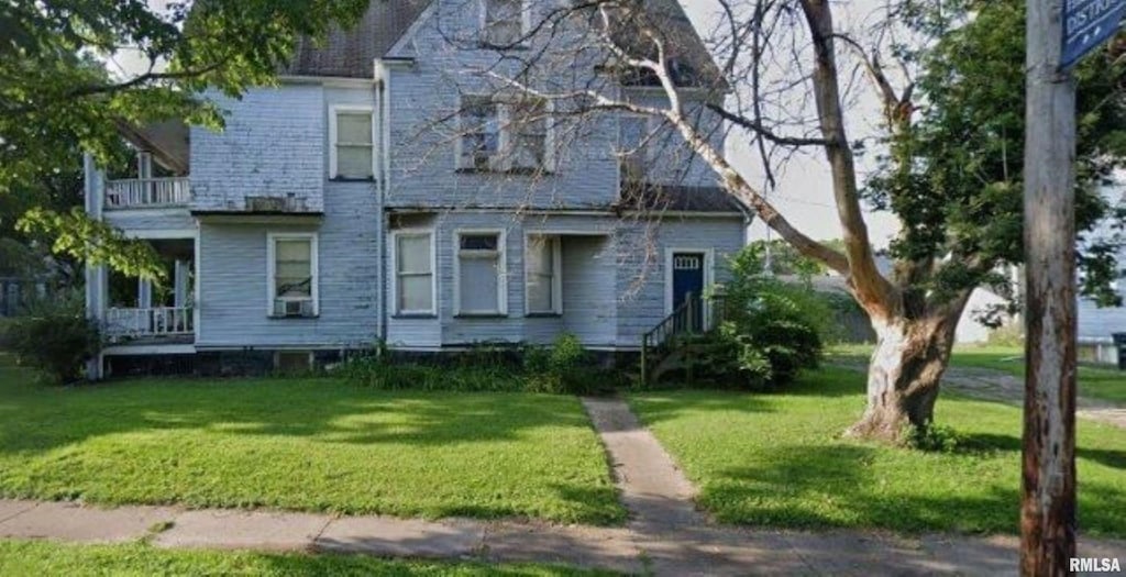 view of front facade with a front lawn and a balcony