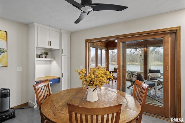 sunroom / solarium featuring a wood stove, a water view, a ceiling fan, vaulted ceiling, and wood finished floors