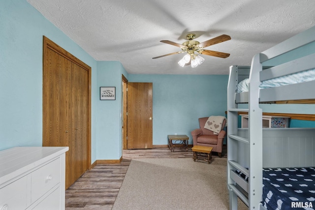 bedroom with wood finished floors, a textured ceiling, and a ceiling fan