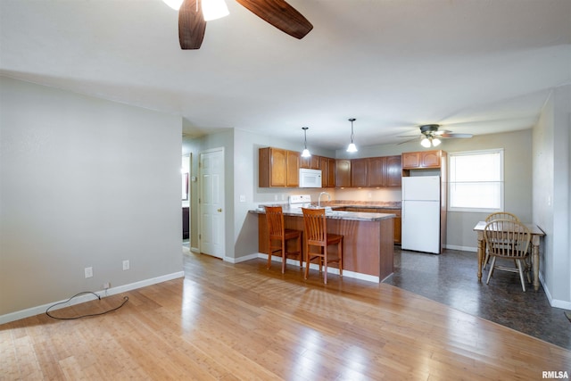12855 Cleveland Ln, Pittsburg, IL 62974 - kitchen with wood-type flooring, ceiling fan, white appliances, and a peninsula