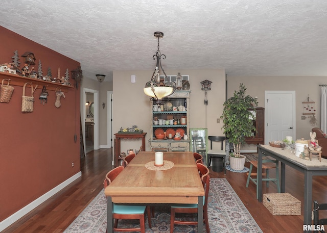 dining area featuring dark wood-style flooring, baseboards, and a textured ceiling