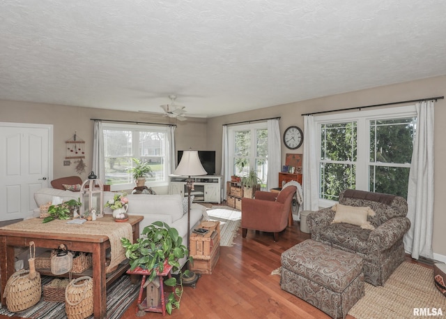 living area with light wood-style floors, ceiling fan, and a textured ceiling