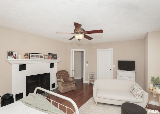 bedroom with a glass covered fireplace, ceiling fan, baseboards, and wood finished floors