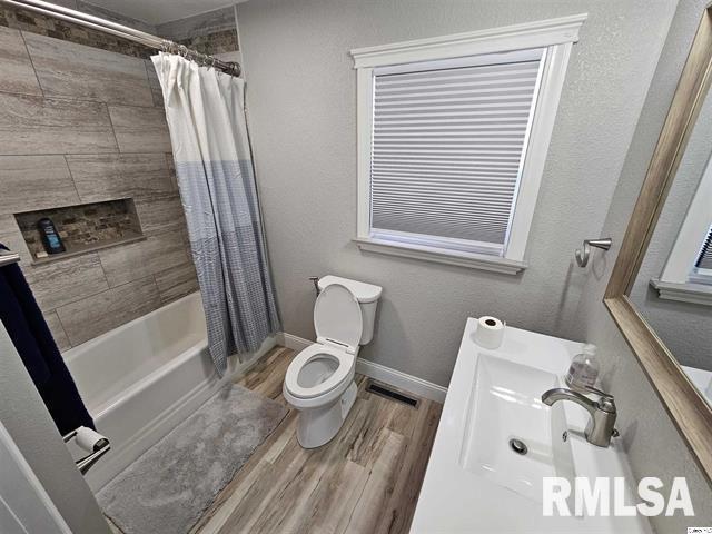 306 Walker St, Ursa, IL 62376 - full bath with vanity, baseboards, toilet, shower / bathtub combination with curtain, and wood finished floors