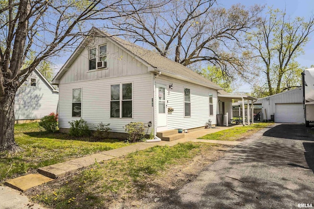 bungalow with entry steps, board and batten siding, driveway, and an outdoor structure