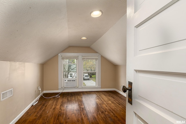 bonus room with visible vents, baseboards, hardwood / wood-style flooring, a textured ceiling, and vaulted ceiling