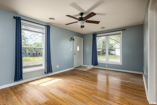 unfurnished room with light wood-style floors, baseboards, visible vents, and a wealth of natural light
