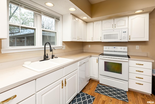 kitchen with light countertops, white appliances, white cabinetry, and a sink