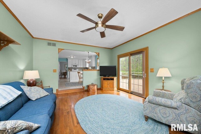 living room featuring visible vents, a ceiling fan, wood finished floors, and ornamental molding