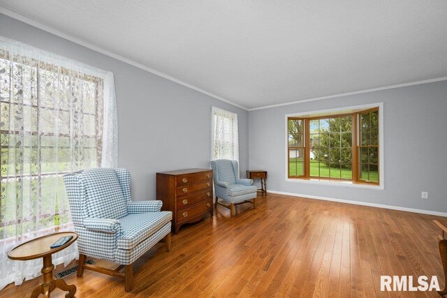 sitting room featuring wood-type flooring, ornamental molding, and baseboards