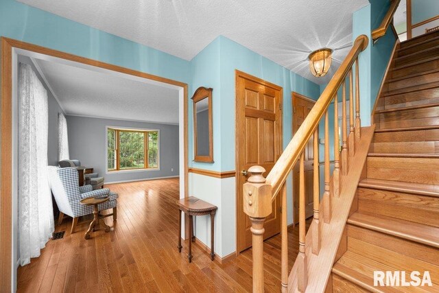 stairway featuring baseboards, a textured ceiling, and wood finished floors