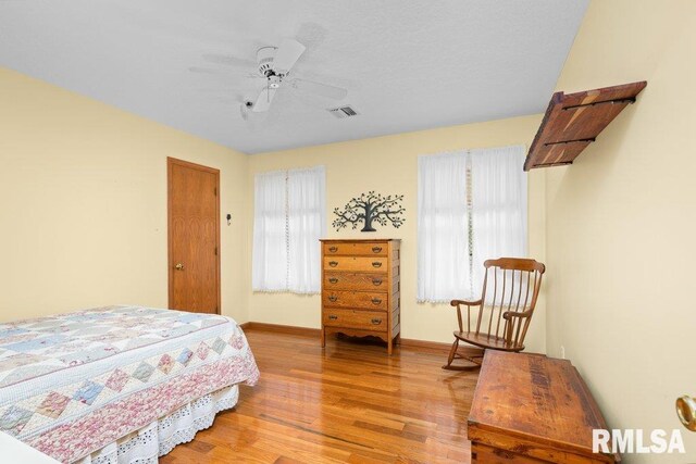 bedroom with visible vents, light wood-style flooring, ceiling fan, and baseboards