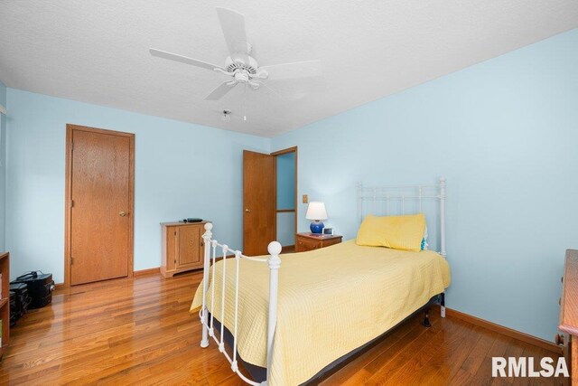 bedroom with a ceiling fan, baseboards, and hardwood / wood-style flooring